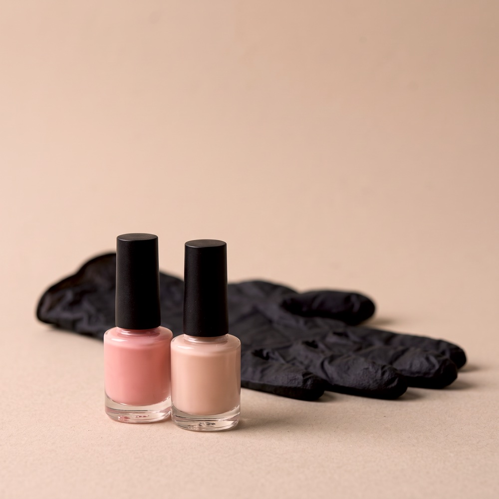 Dos frascos de gel polish, rosa y nude, delante de un guante negro